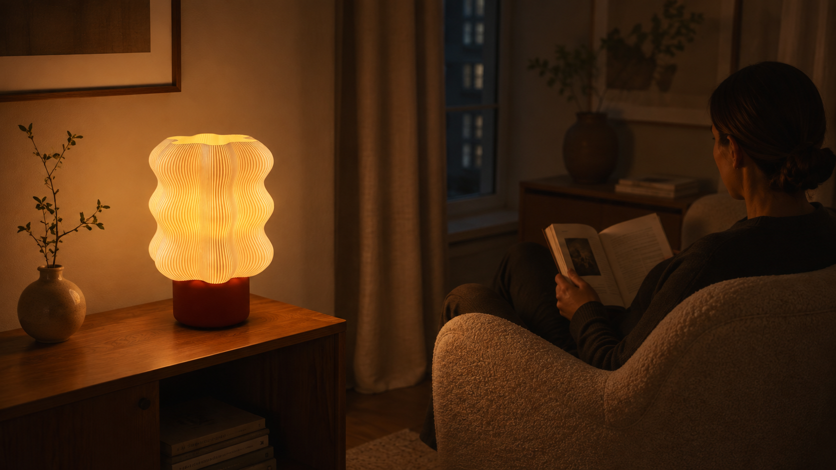En person læser i en lænestol i et dæmpet lyst rum, oplyst af den bløde lyspøl fra en SETTLE-lampe